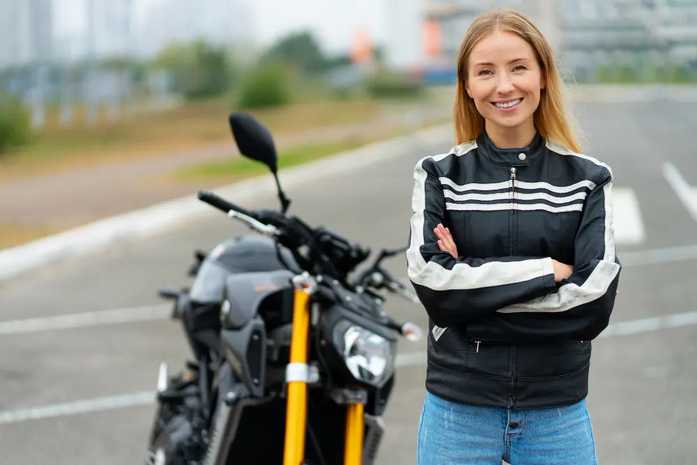 bella ragazza bionda sorride accanto a moto nera