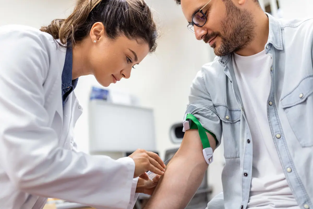 infermiera cerca vena per far donare sangue a uomo