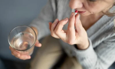 signora seduta prende pillola della pressione