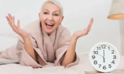 signora sorride con mani aperte accanto a orologio