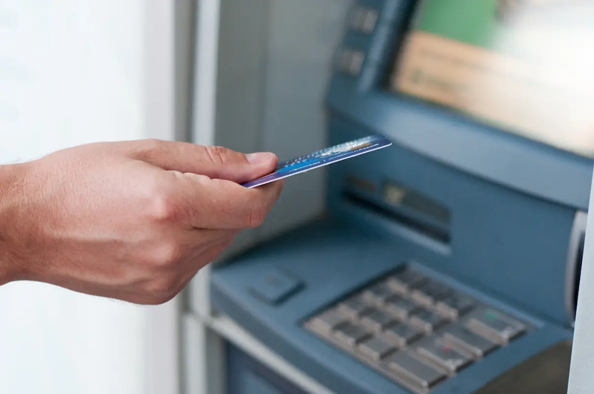 uomo preleva soldi da un atm con la carta di debito