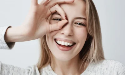 bionda sorride mostrando denti con ok su occhio
