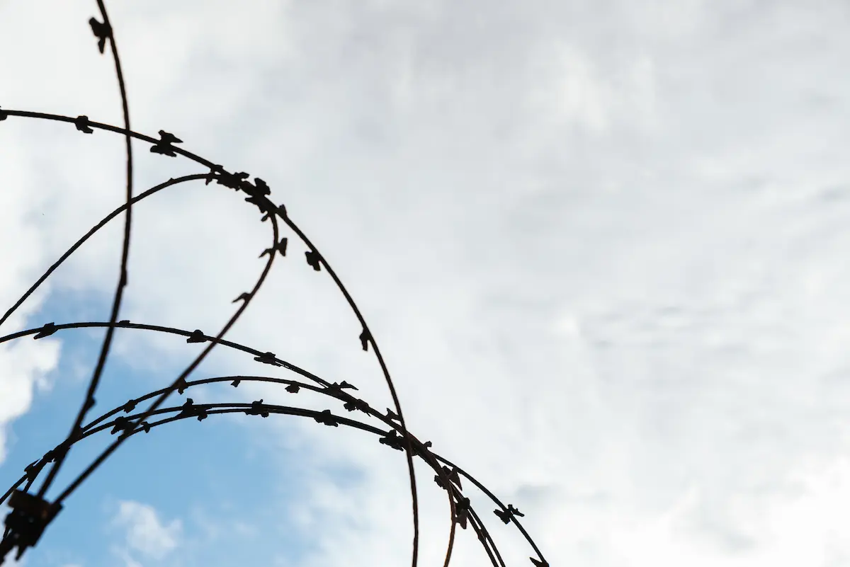 filo spinato di un carcere sotto il cielo azzurro
