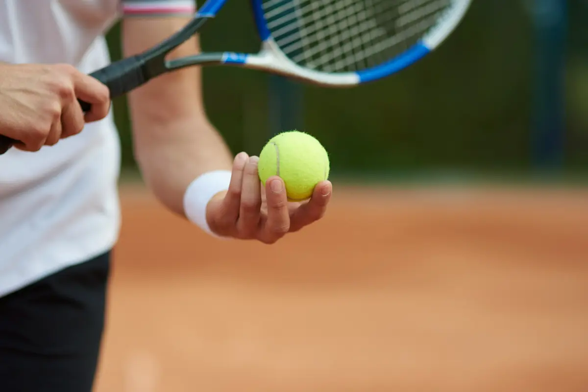 giocatore di tennis tiene in mano pallina gialla