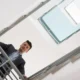 lavoratore guarda in basso da una scala