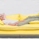 persona anziana sorride sdraiata su divano giallo