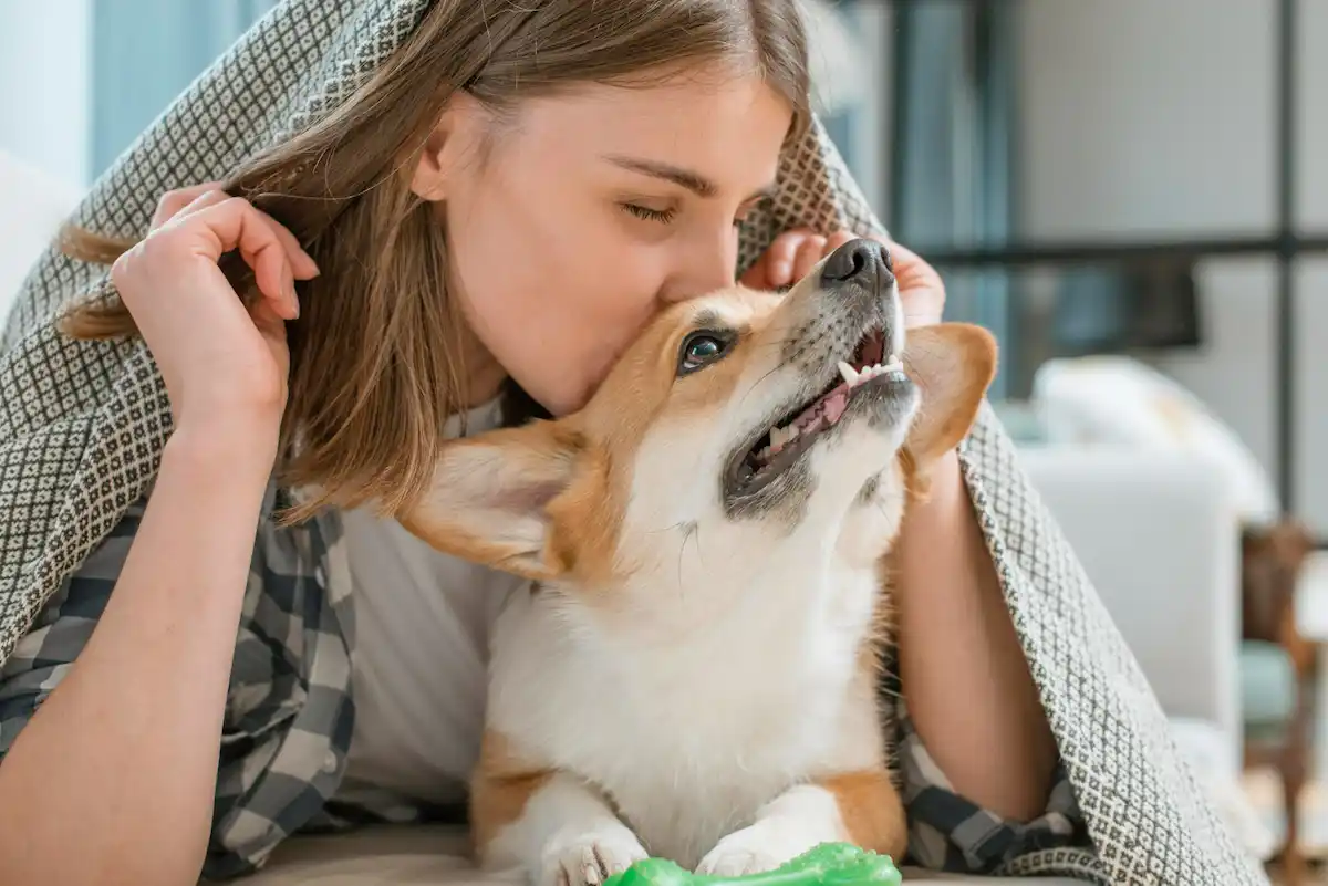 ragazza bacia cane in testa sul letto