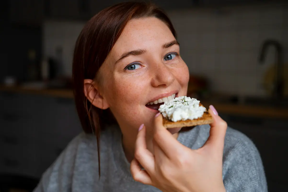 ragazza mangia una tartina con formaggio