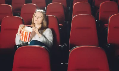 ragazza seduta in un cinema vuoto con popcorn
