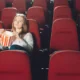 ragazza seduta in un cinema vuoto con popcorn