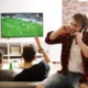 ragazzo telefona mentre amici guardano calcio in tv