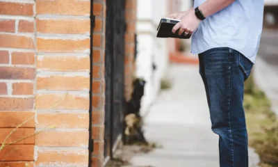 uomo con libro fermo davanti a un muro