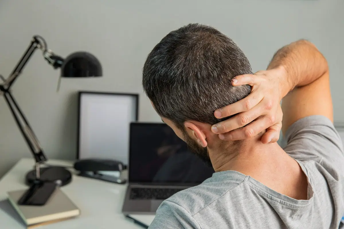 uomo davanti al pc con dolore alla cervicale