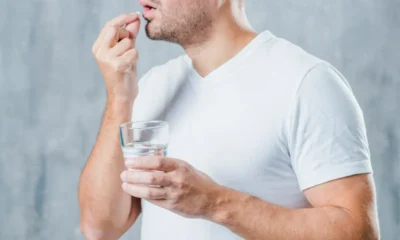 uomo prende una pasticca con bicchiere d'acqua
