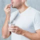 uomo prende una pasticca con bicchiere d'acqua