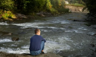 uomo seduto guarda fiume scorrere