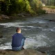 uomo seduto guarda fiume scorrere