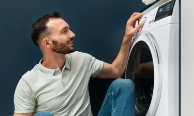 uomo sorride davanti a lavatrice