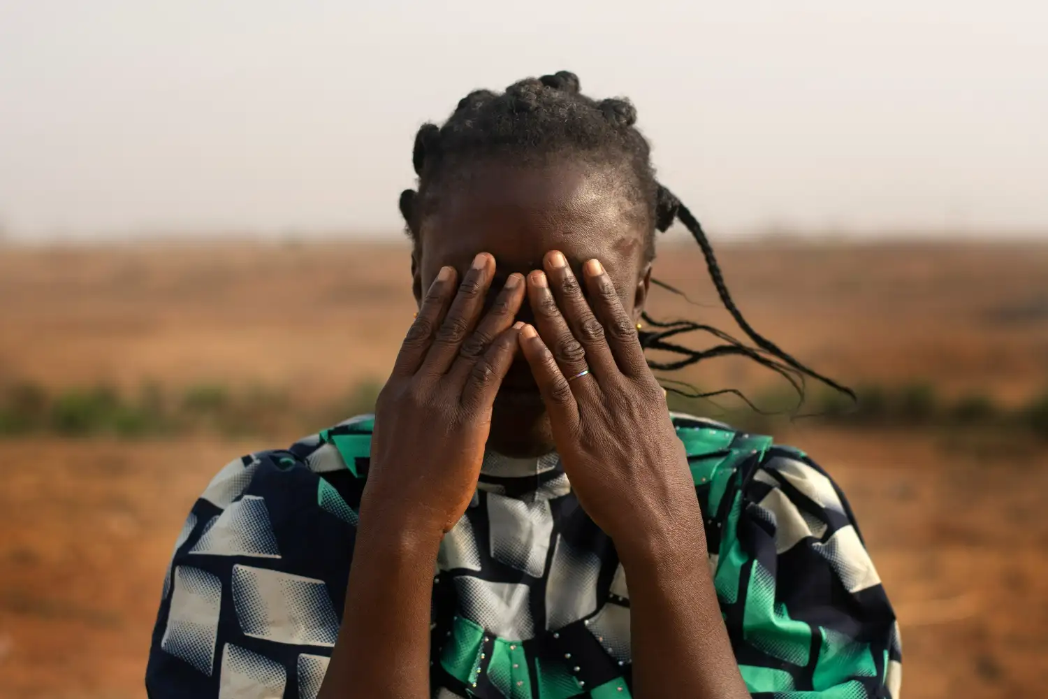 donna del sudan con mani sul viso