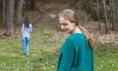 donna si gira triste con in fondo figlia che va via