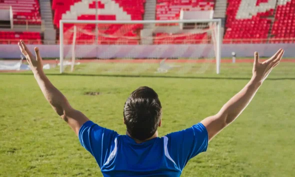 calciatore braccia aperte stadio