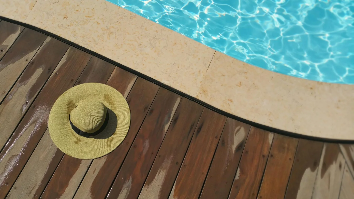 Terreno exterior con una piscina y una tarima de madera para ilustrar come camuffare una piscina fuori terra de forma elegante en el jardín