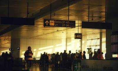 Personas esperando en el aeropuerto por che significa overbooking aereo y un posible cambio de embarque