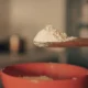 Spoon with baking powder for illustrating che cos'è il cremor tartaro in a home baking context