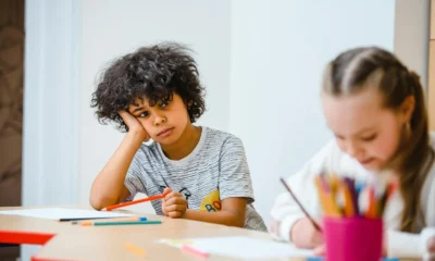 Un estudiante aburrido frente a su escritorio, ilustrando la idea de "chi è attivo non sa cosa sia" en el contexto de una definición de crucigrama.