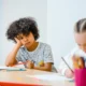 Un estudiante aburrido frente a su escritorio, ilustrando la idea de "chi è attivo non sa cosa sia" en el contexto de una definición de crucigrama.