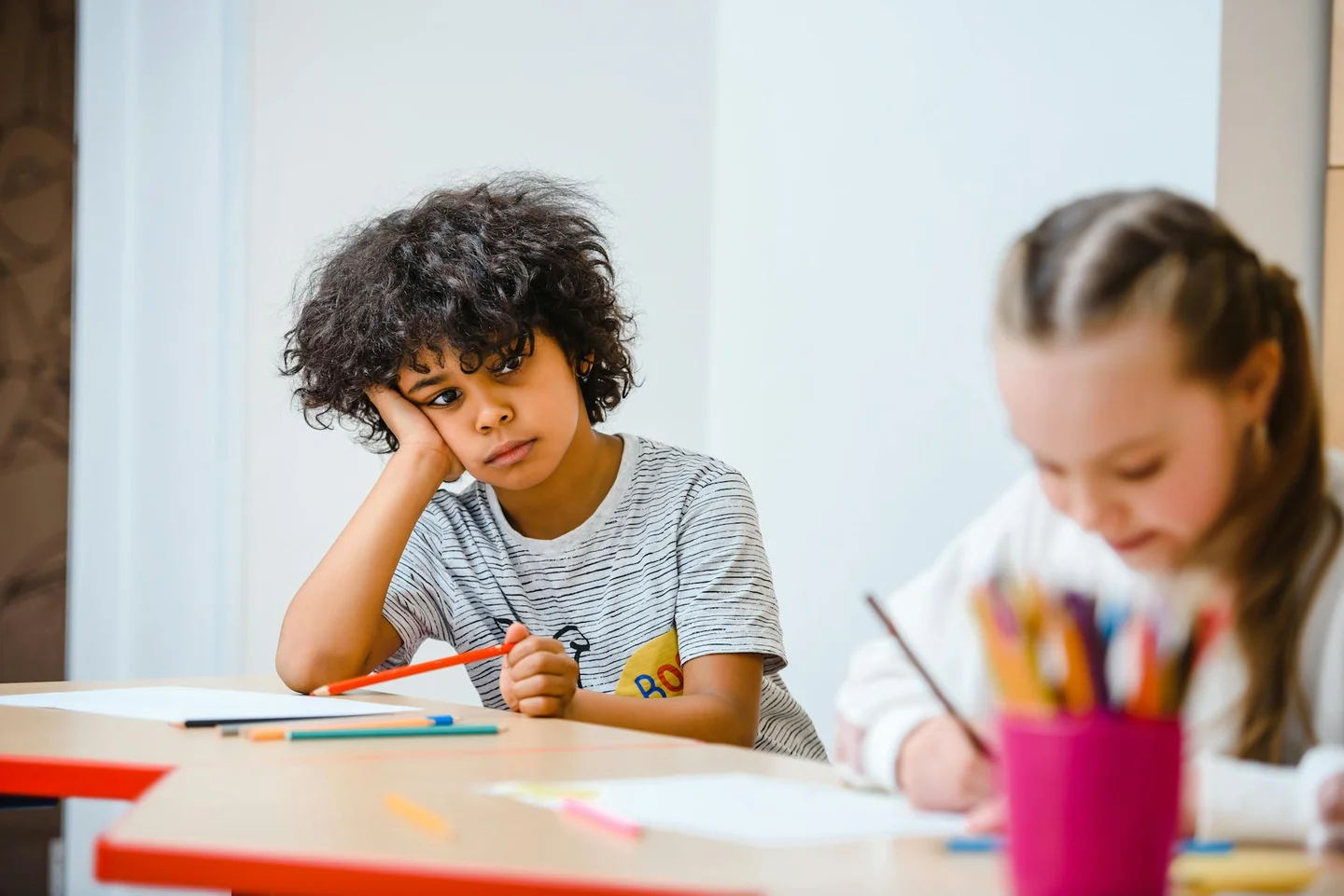 Un estudiante aburrido frente a su escritorio, ilustrando la idea de "chi è attivo non sa cosa sia" en el contexto de una definición de crucigrama.