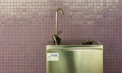 Persona revisando si si può bere l’acqua del rubinetto all’estero antes de llenar un vaso en la cocina de un hotel