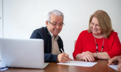 Pareja de personas mayores firmando documentos sobre herencia, relacionado con chi può fare testamento