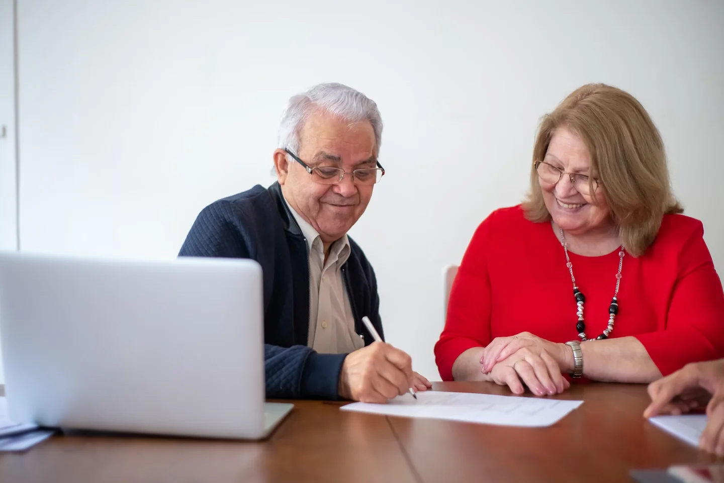 Pareja de personas mayores firmando documentos sobre herencia, relacionado con chi può fare testamento