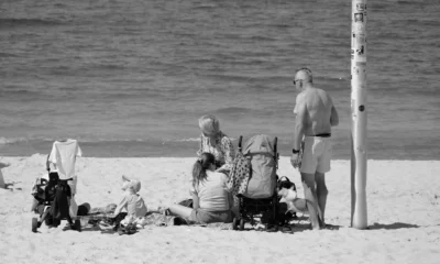 Familia con cochecito en la playa para ilustrar 'dove andare in vacanza con un neonato' y mostrar una escapada tranquila junto al mar.