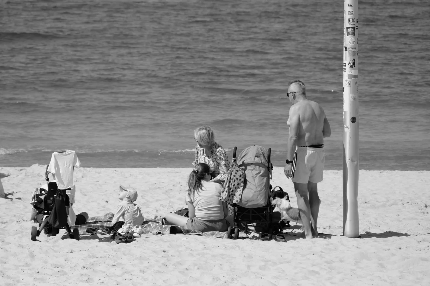 Familia con cochecito en la playa para ilustrar 'dove andare in vacanza con un neonato' y mostrar una escapada tranquila junto al mar.