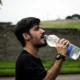 Imagen de un hombre bebiendo agua para ilustrar quanto bere quando fa caldo en una situación de calor y deshidratación.