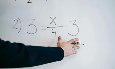 Profesor explicando come si calcola l'area del quadrato en una pizarra con fórmulas geométricas