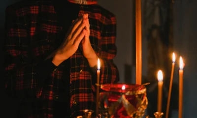 Imagen de manos en oración junto a una vela, evocando perche la vostra gioia sia piena en un contexto de recogimiento espiritual.