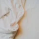Persona cosiendo un lenzuolo para come fare gli angoli alle lenzuola en una mesa de trabajo