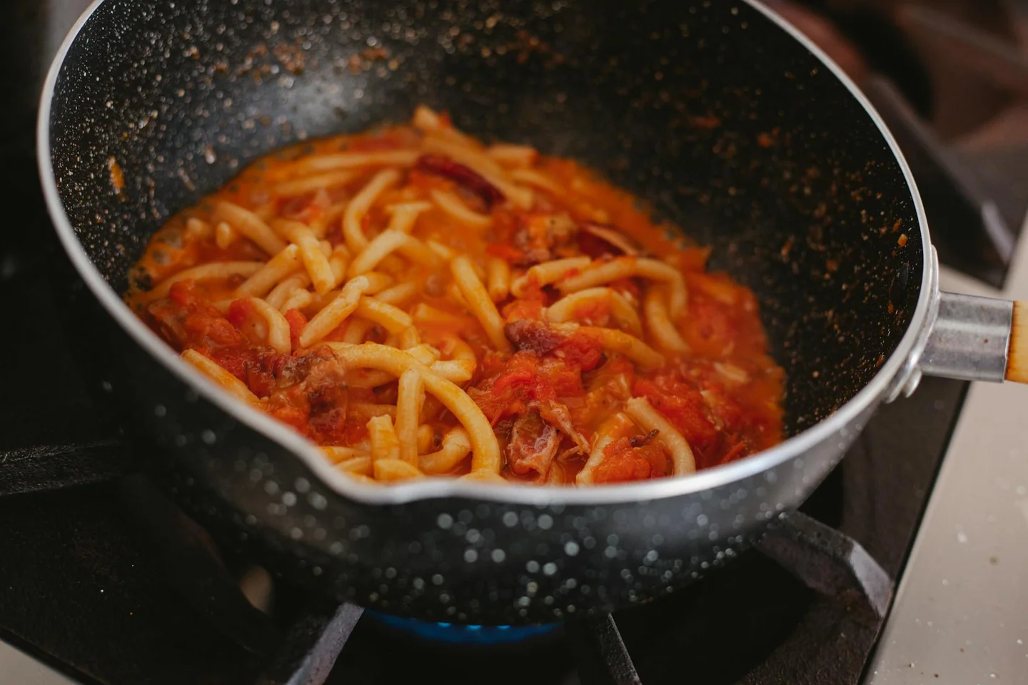 Una olla con salsa de tomate a fuego lento para ilustrar "quanto deve cuocere la passata di pomodoro" en una cocina casera.