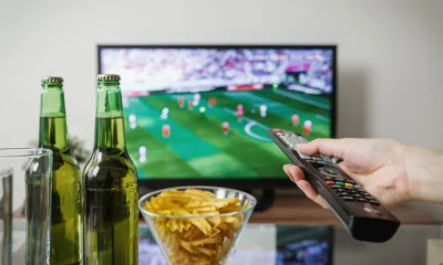 Persona viendo un partido para "dove vedere i Mondiali in TV e streaming" en la televisión de casa, con ambiente de fútbol y pantalla grande.