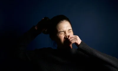 Imagen de una mujer estornudando en interiores para ilustrar quale allergia dà stanchezza y el malestar respiratorio asociado.