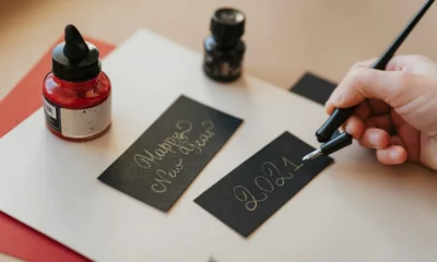 Persona escribiendo un mensaje para "cosa scrivere su biglietto per inaugurazione" en una tarjeta de felicitación junto a un regalo